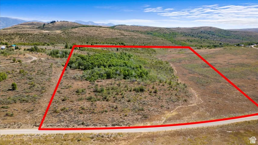 Overview of rural landscape featuring a mountainous background and property boundaries highlighted