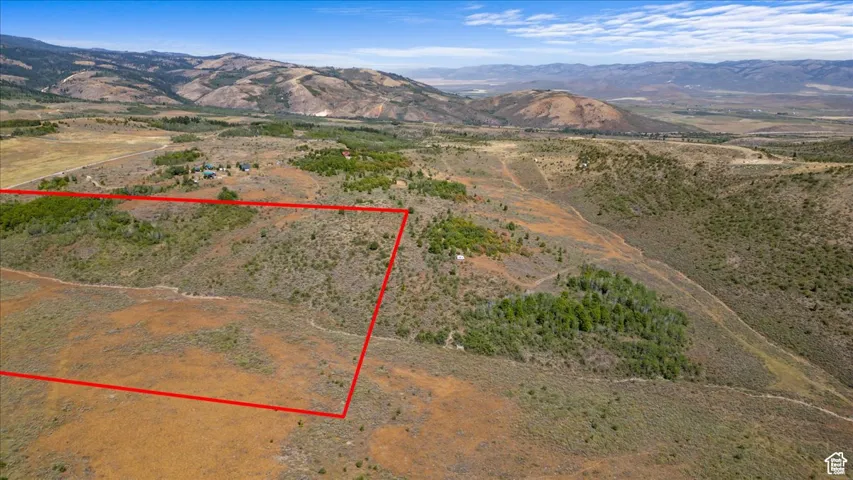 Aerial view of sparsely populated area with property parcel outlined and mountains