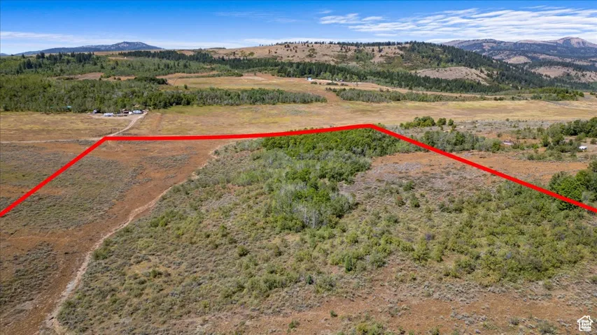 Aerial view of property and surrounding area featuring a mountain backdrop and property parcel outlined