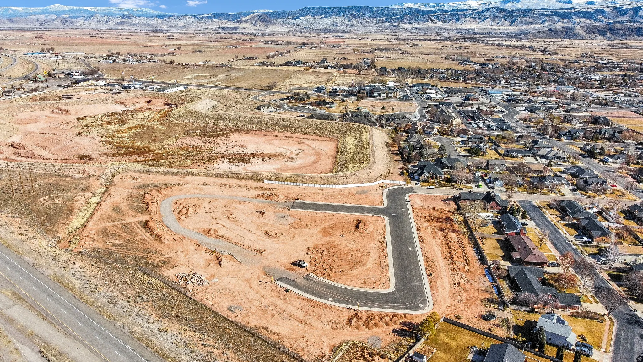 Aerial view of property and surrounding area with a mountainous background and nearby suburban area
