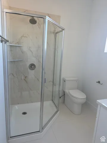 Bathroom featuring light tile patterned floors, vanity, and a marble finish shower