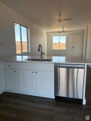 Kitchen with dishwasher, white cabinets, dark wood-style floors, and light stone countertops