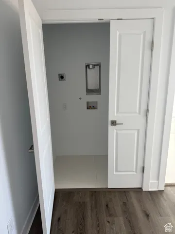 Hallway with wood finished floors and baseboards laundry hook up