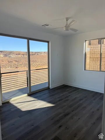 Unfurnished room featuring dark wood-type flooring and ceiling fan