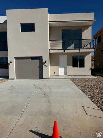 Contemporary home featuring stucco siding, a balcony, an attached garage, and concrete driveway