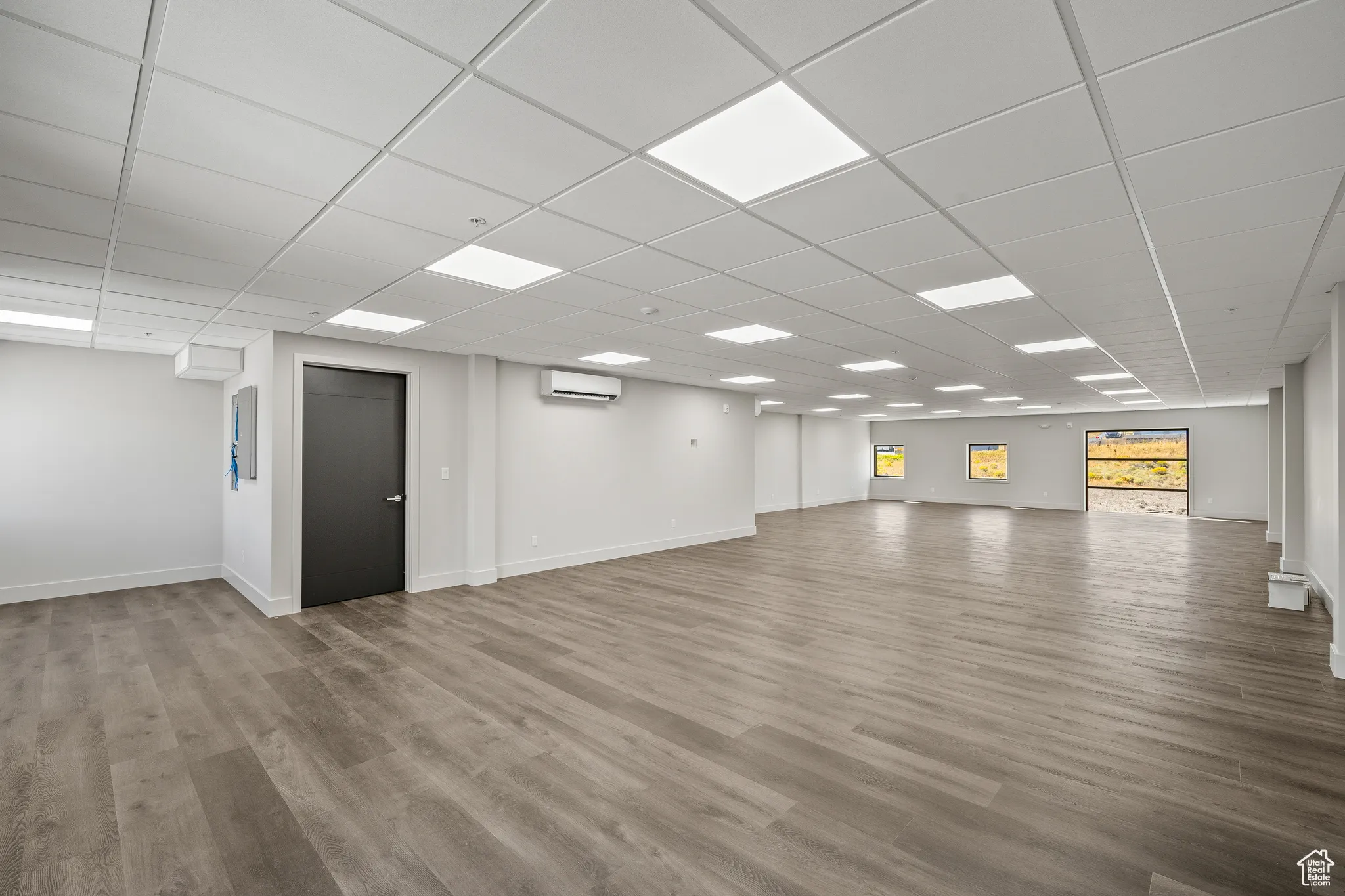 Spare room with light wood finished floors, a paneled ceiling, and a wall mounted air conditioner