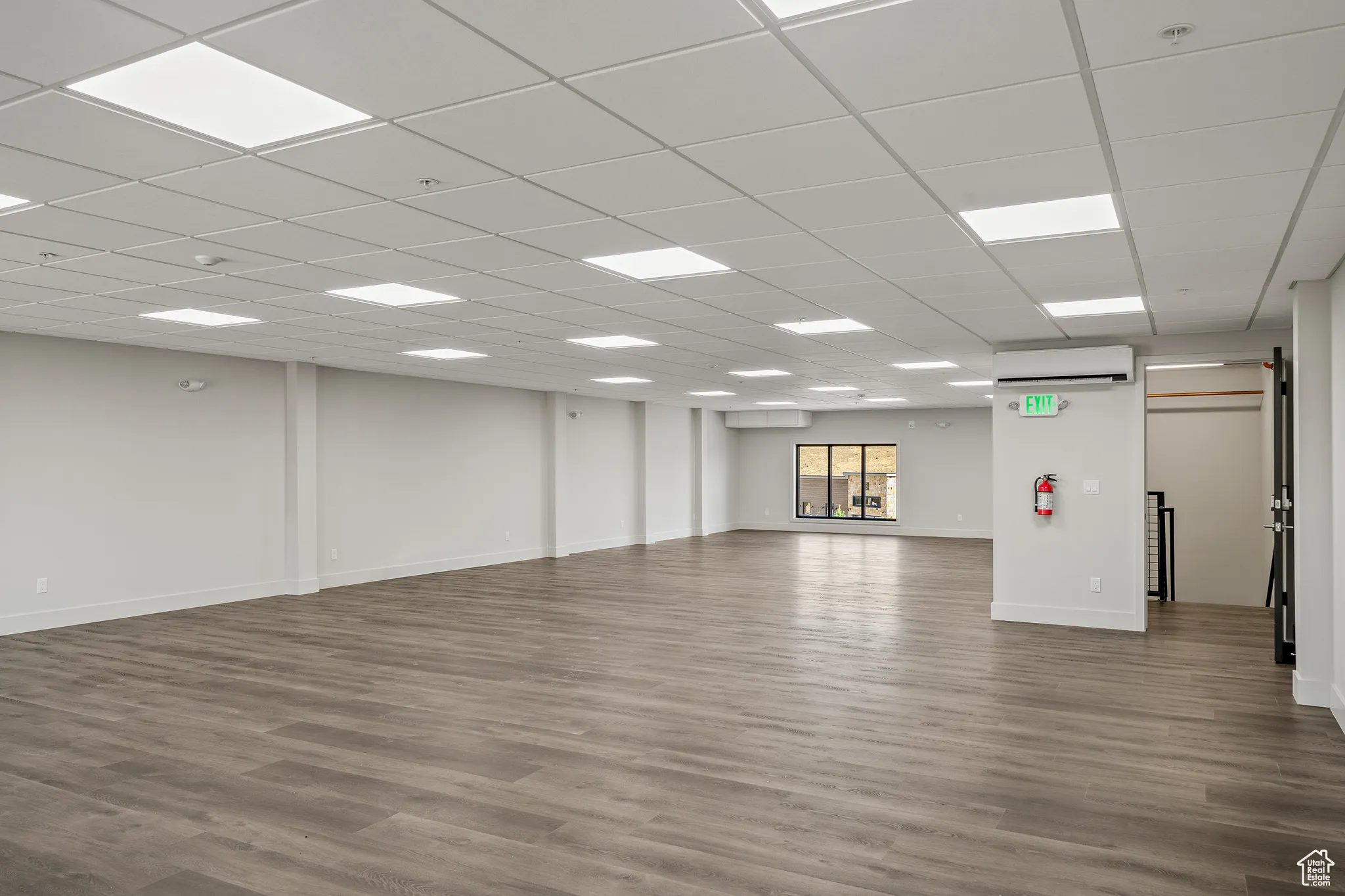 Spare room with dark wood finished floors, a paneled ceiling, and a wall mounted AC