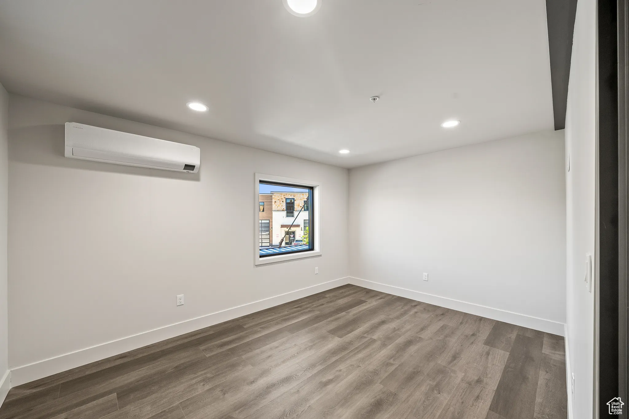Empty room with wood finished floors, recessed lighting, and a wall mounted air conditioner