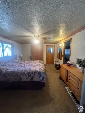 Bedroom featuring dark colored carpet, ceiling fan, and a textured ceiling