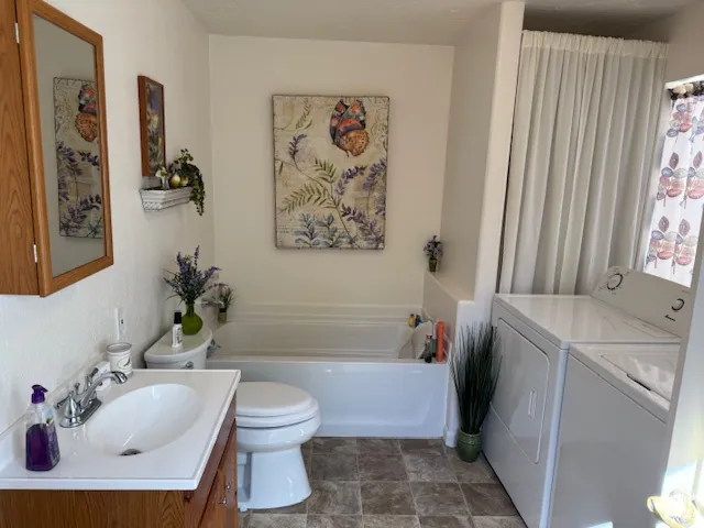 Bathroom with a bath, vanity, and washing machine and clothes dryer