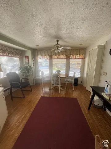 Dining area featuring wood finished floors, a textured ceiling, and ceiling fan