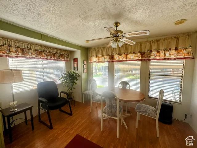 Dining room with a ceiling fan, wood finished floors, and a textured ceiling