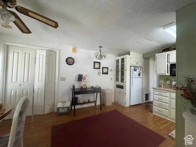 Kitchen featuring white cabinets, a textured ceiling, dark wood-type flooring, a chandelier, and light countertops