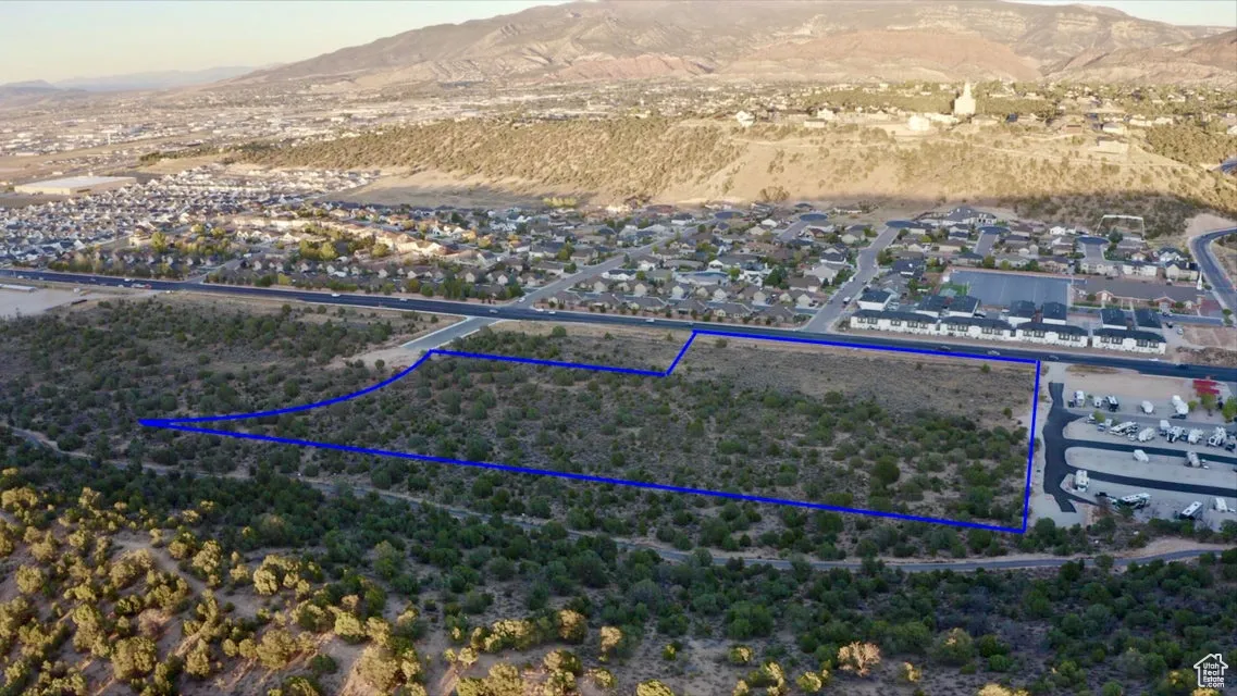 Aerial view of residential area with property boundaries highlighted and a mountain backdrop