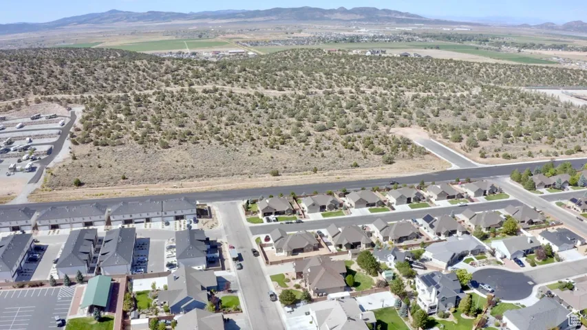 Aerial view of property and surrounding area featuring a mountainous background and nearby suburban area