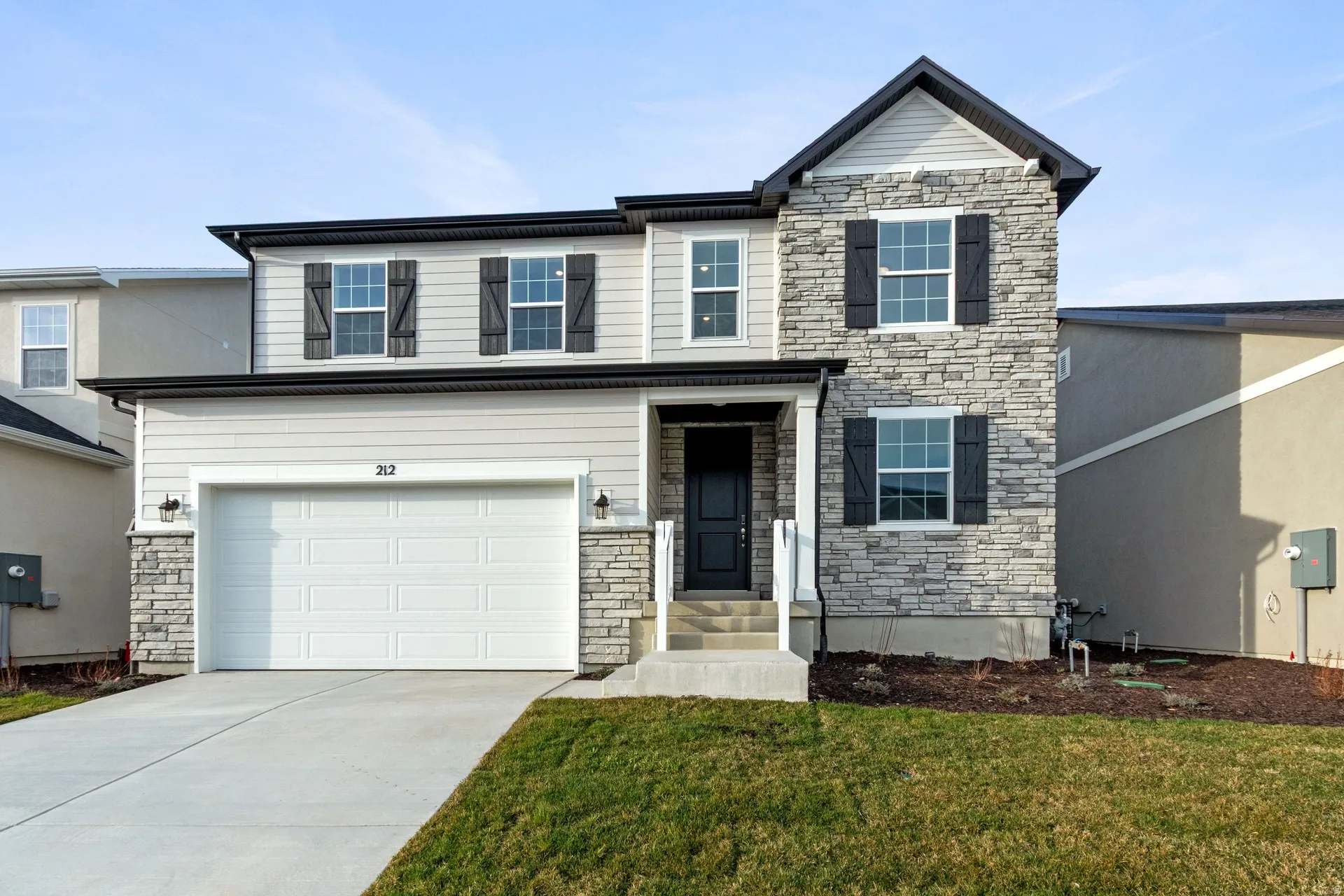View of front of home featuring stone siding, an attached garage, concrete driveway, and a front yard