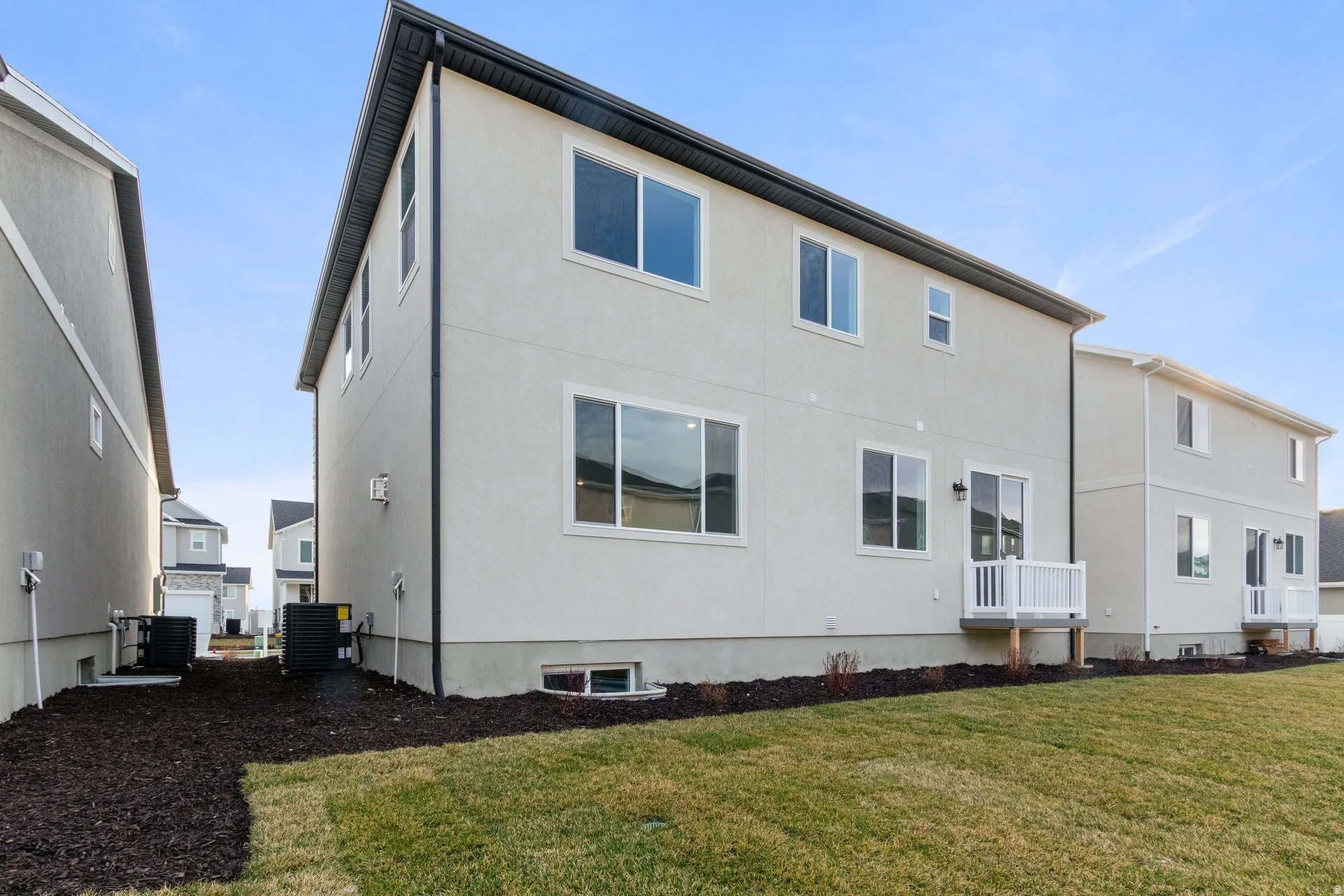 Back of house with a lawn and stucco siding