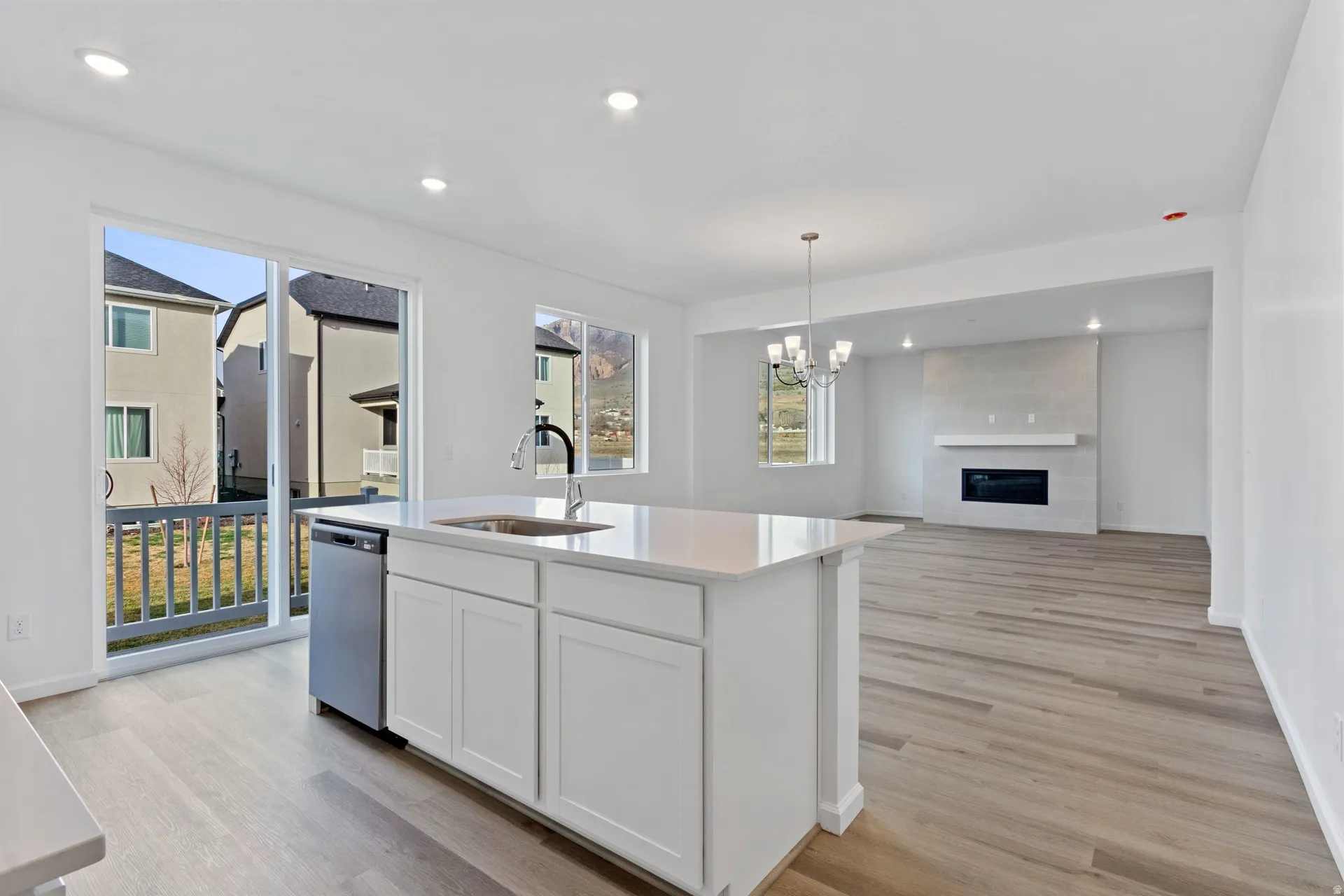 Kitchen featuring a fireplace, open floor plan, light wood-type flooring, and light stone countertops