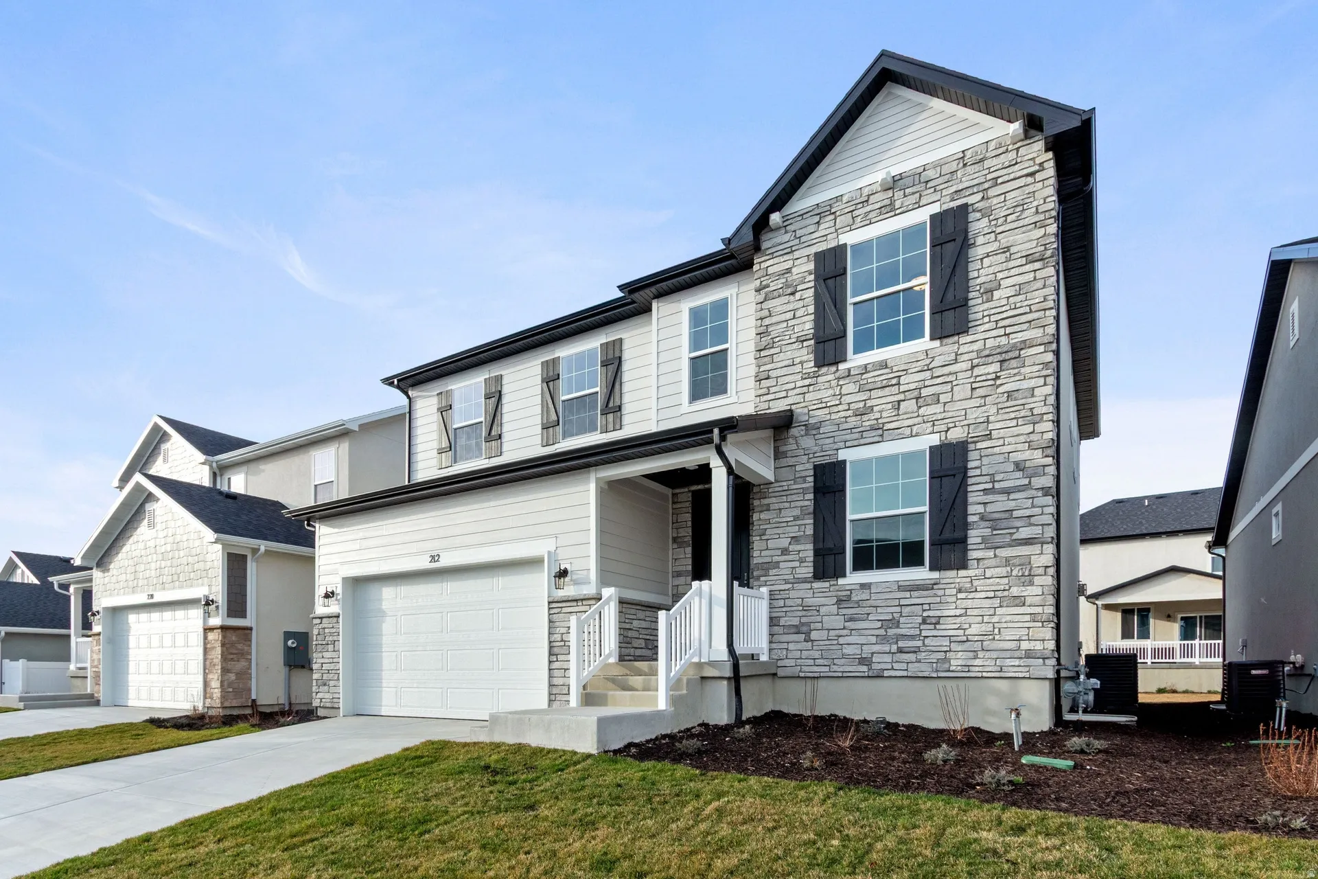 View of front of home featuring stone siding, a garage, concrete driveway, and a front yard