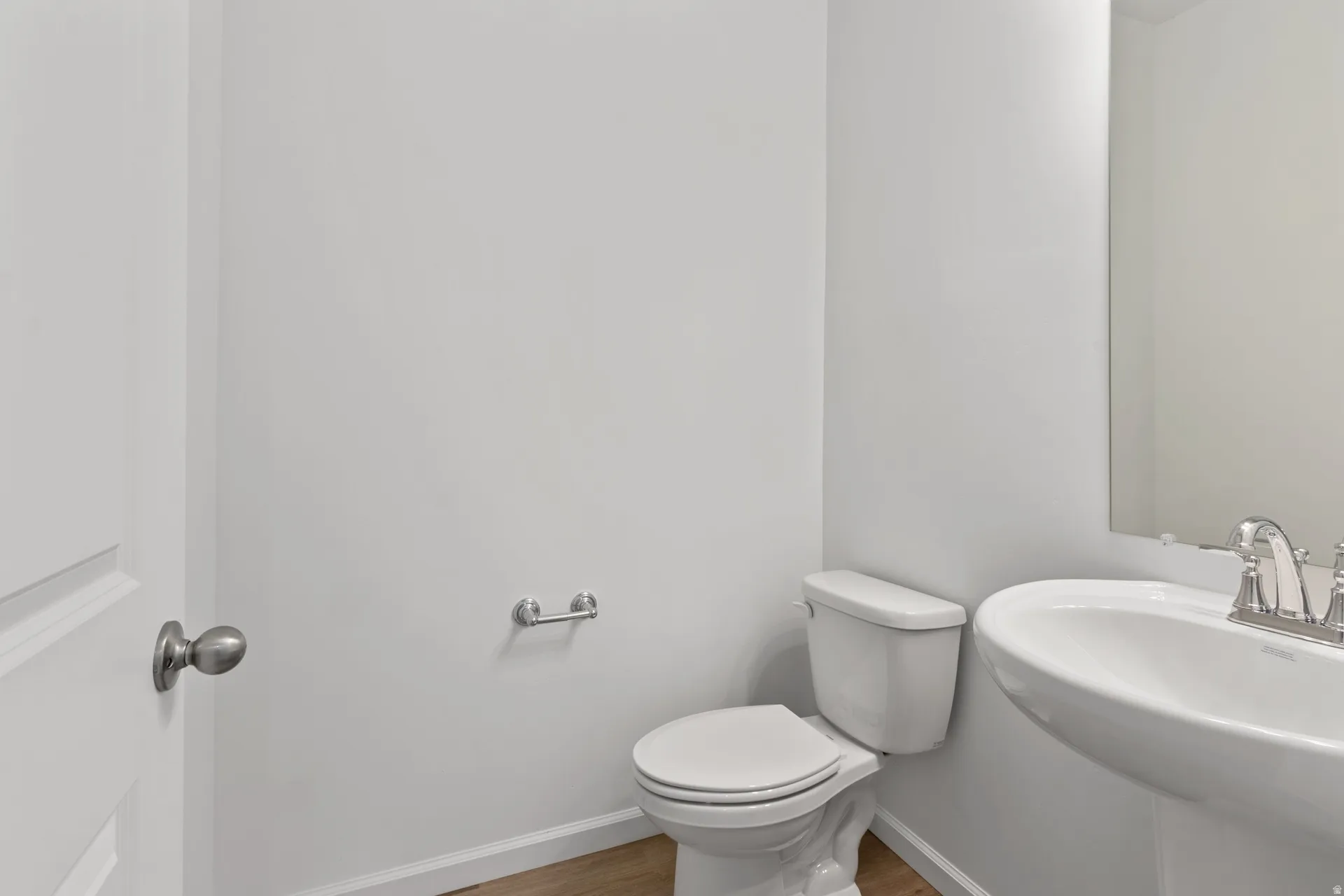 Half bathroom with toilet and wood finished floors