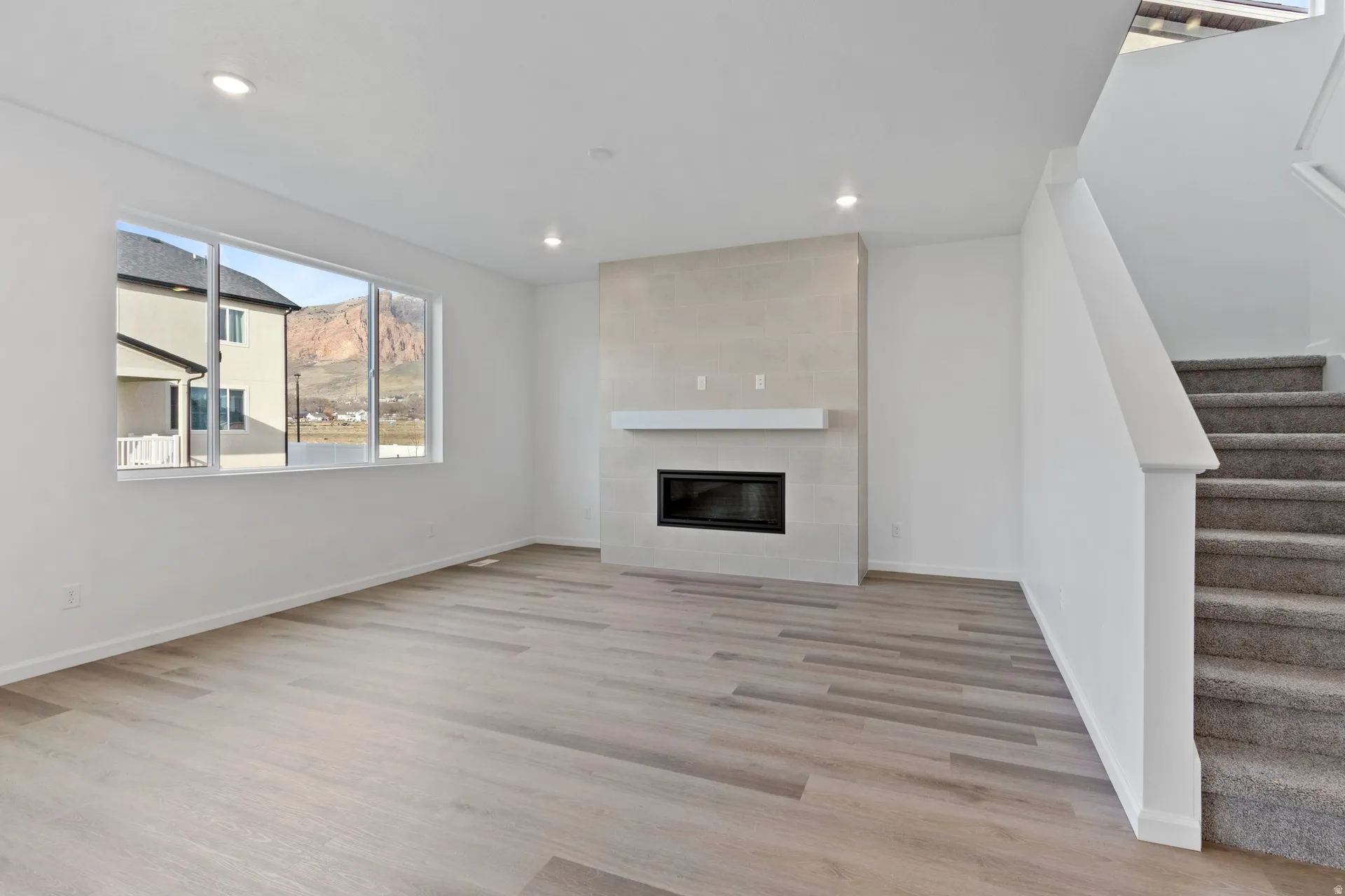 Unfurnished living room with recessed lighting, light wood-style flooring, and a tiled fireplace