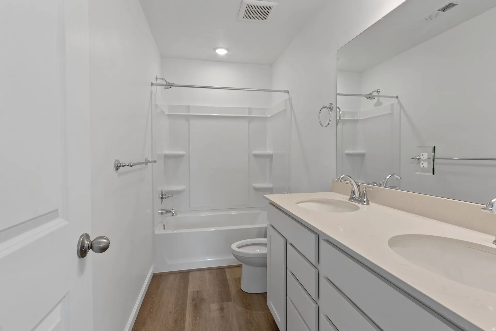 Full bath with double vanity, dark wood-type flooring, and tub / shower combination