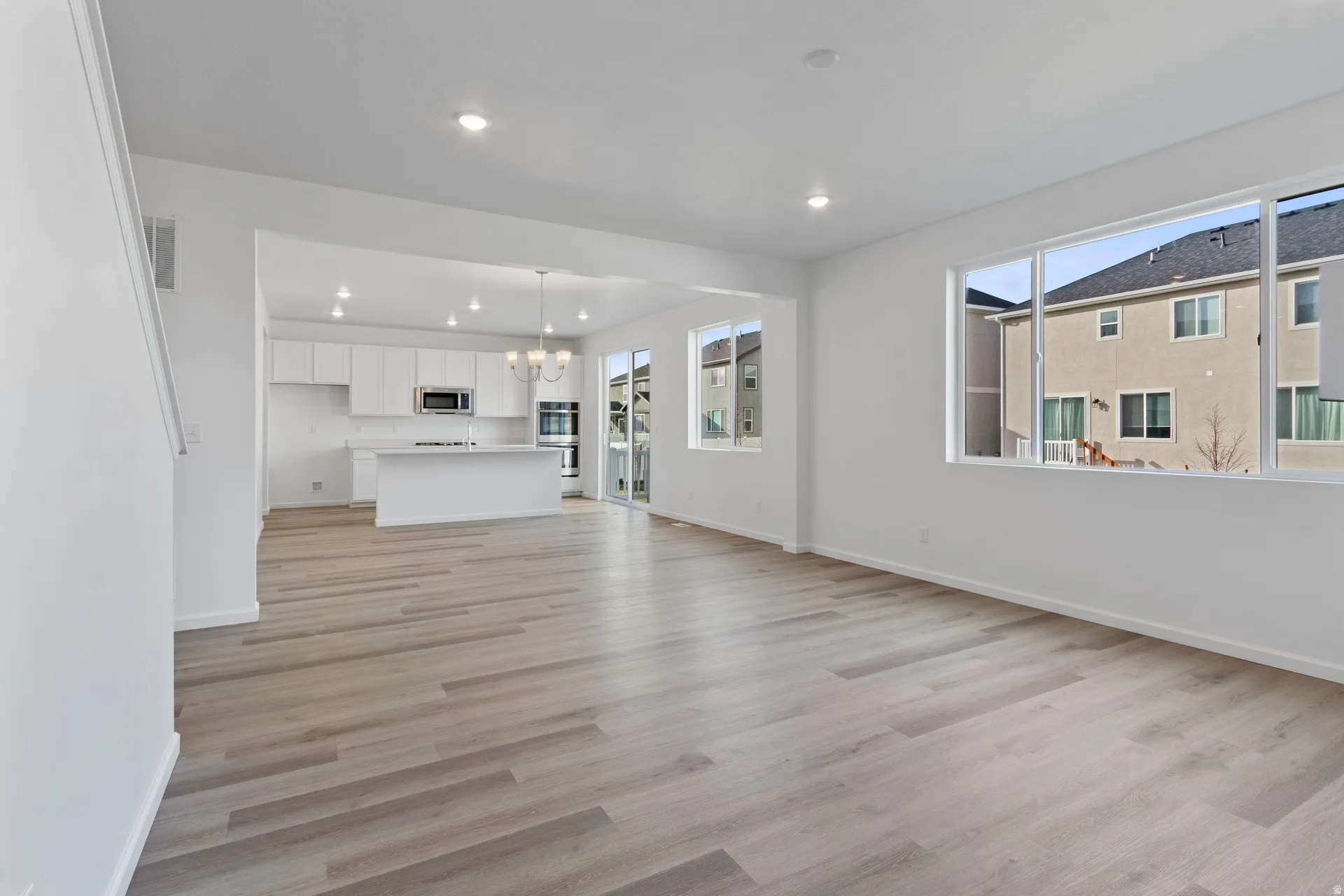 Unfurnished living room with a chandelier and light wood-type flooring