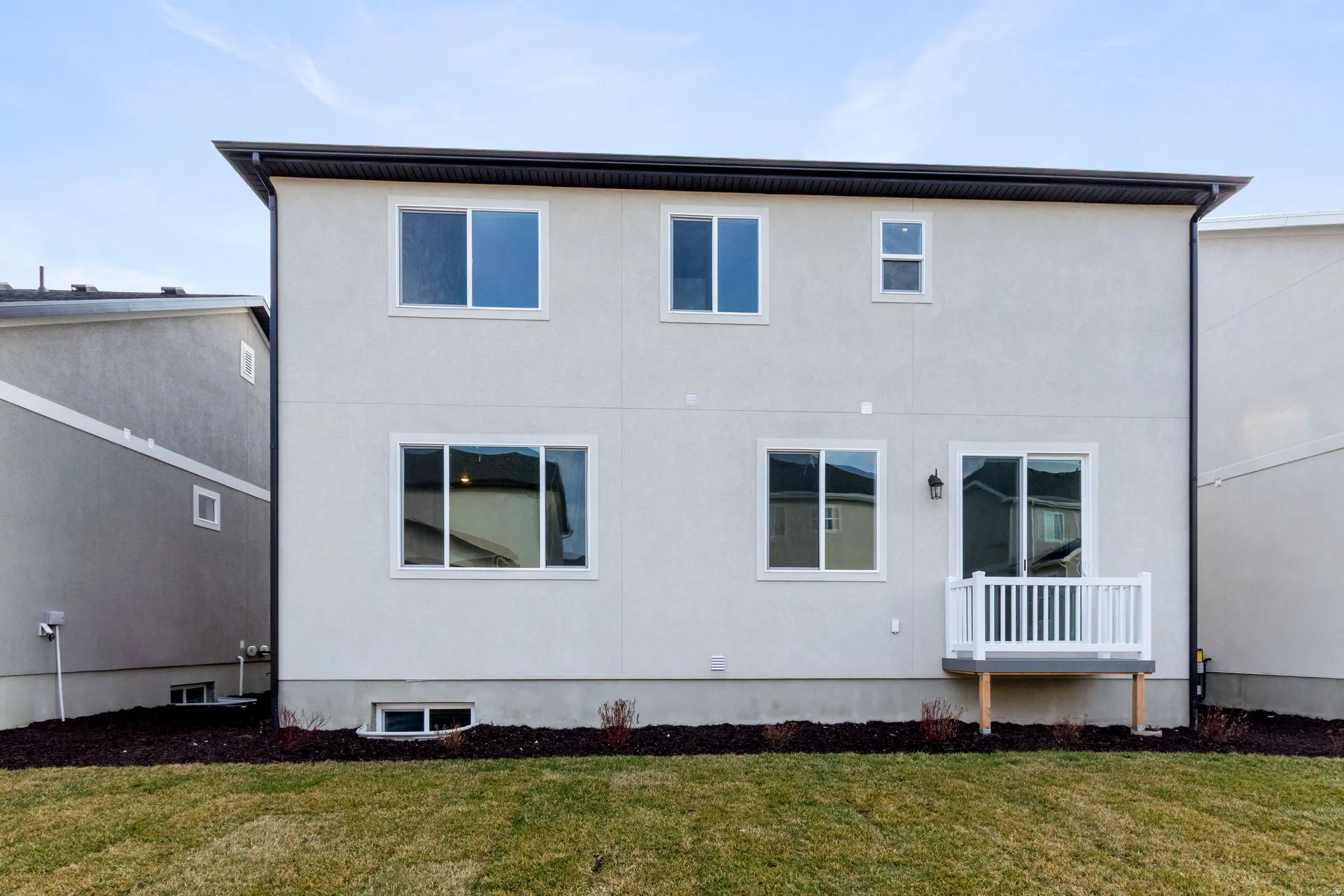 Back of property with a lawn and stucco siding