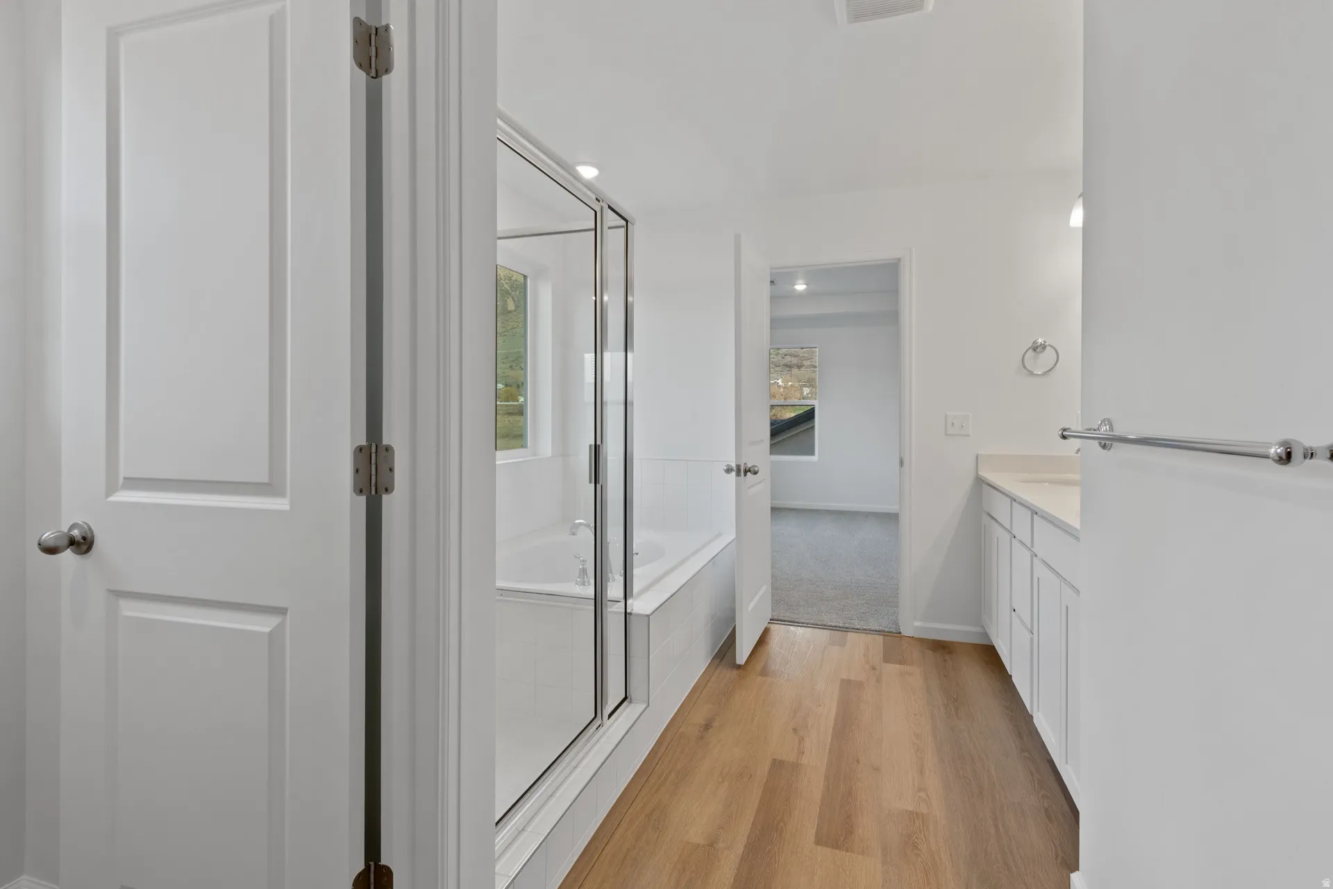 Primary bathroom featuring a bath, vanity, a shower stall, light wood-style flooring, and recessed lighting
