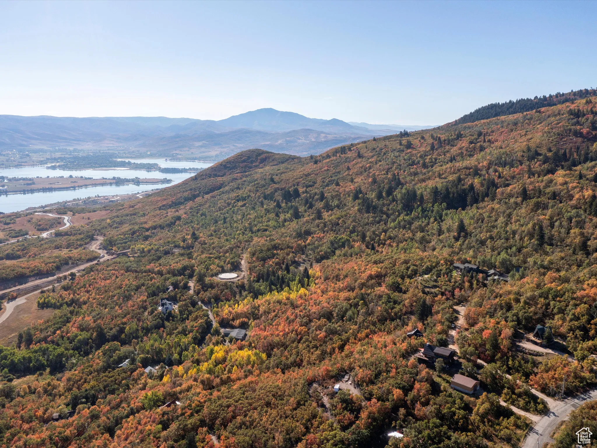 View of mountain backdrop featuring a nearby body of water and a heavily wooded area