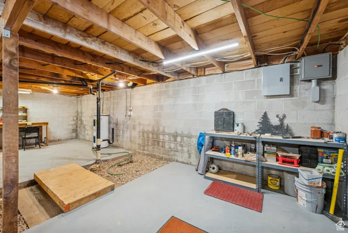 Unfinished basement featuring electric panel and electric water heater