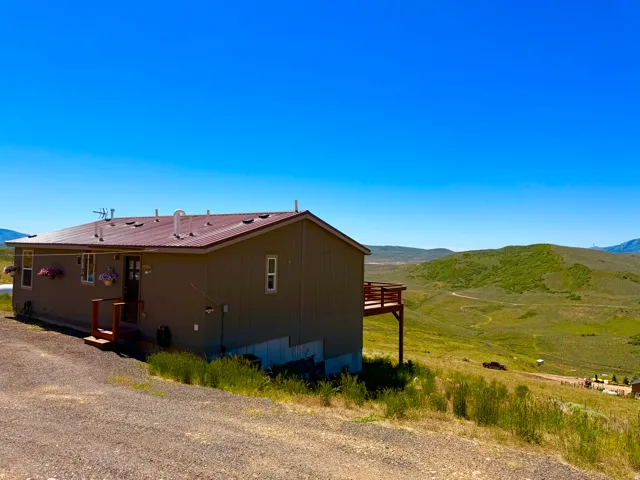 Property exterior featuring a brown metal roof and siding, a front entry with a small porch, and a rear deck