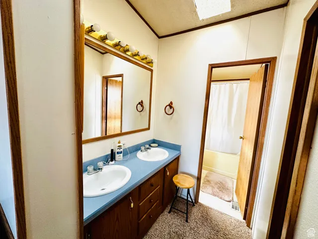 Full bathroom featuring shower / tub combo, double vanity, and skylight