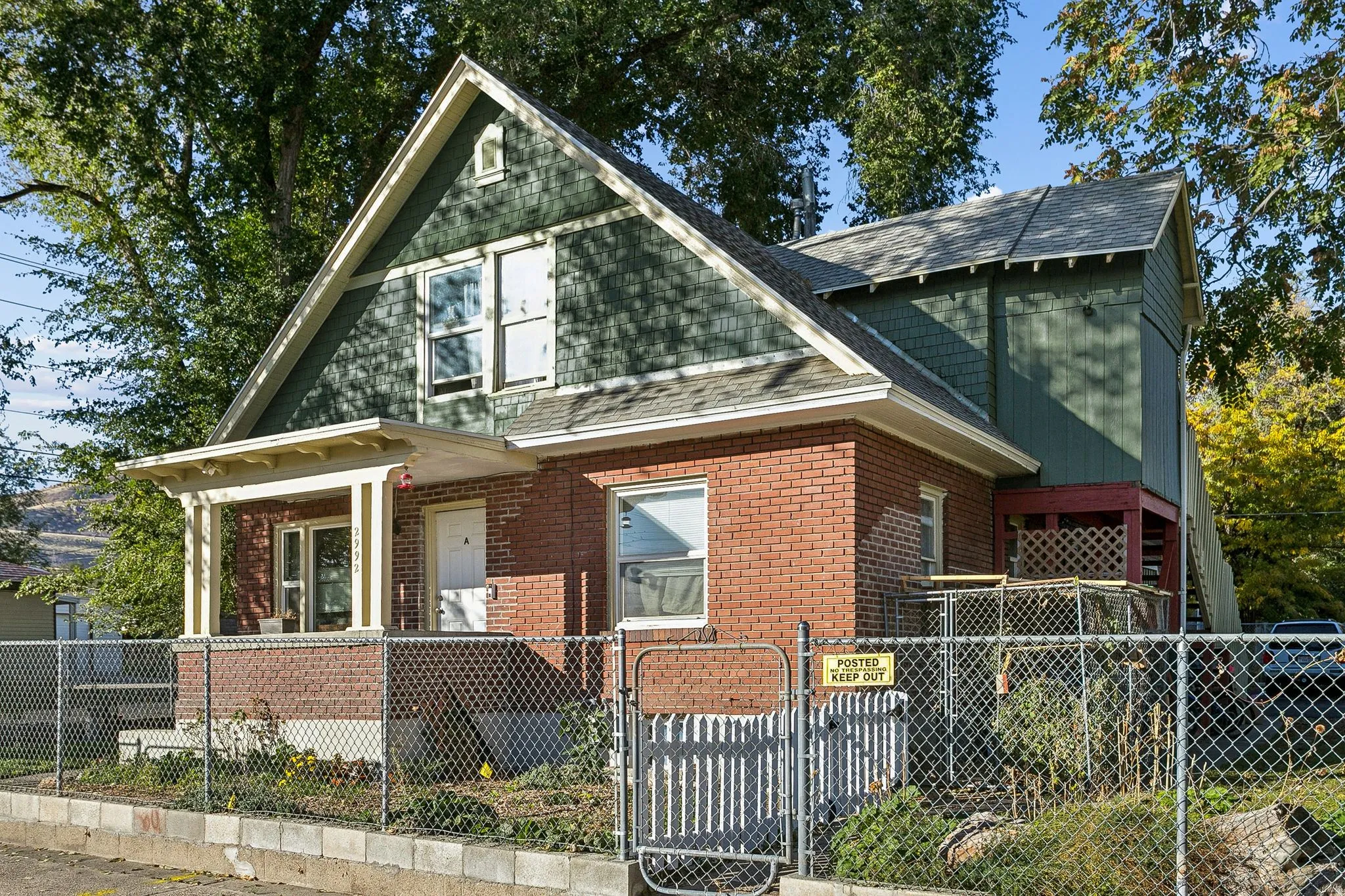 View of front of property with a fenced front yard, a gate, a shingled roof, and brick siding