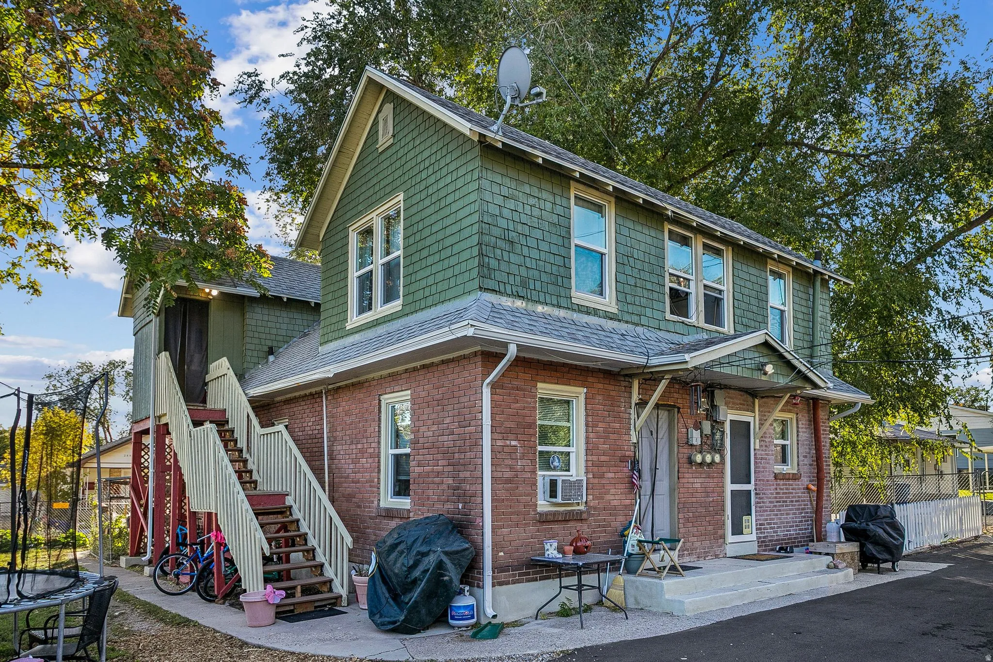 View of front of house with a trampoline, brick siding, roof with shingles, and cooling unit
