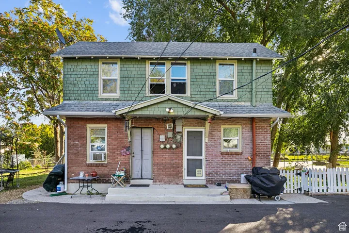 View of front facade with a shingled roof and brick siding