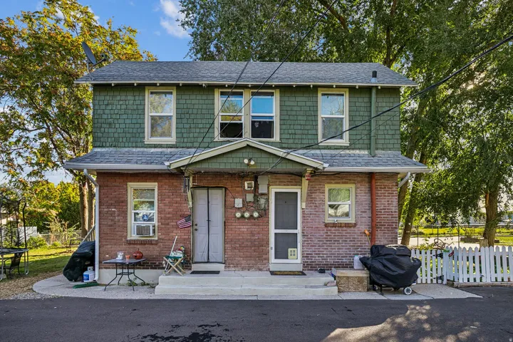 View of front facade with a shingled roof and brick siding