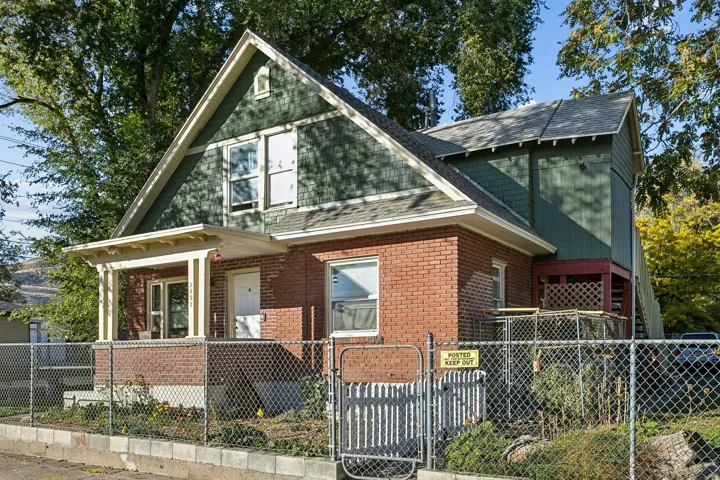 View of front of property with a fenced front yard, a gate, a shingled roof, and brick siding