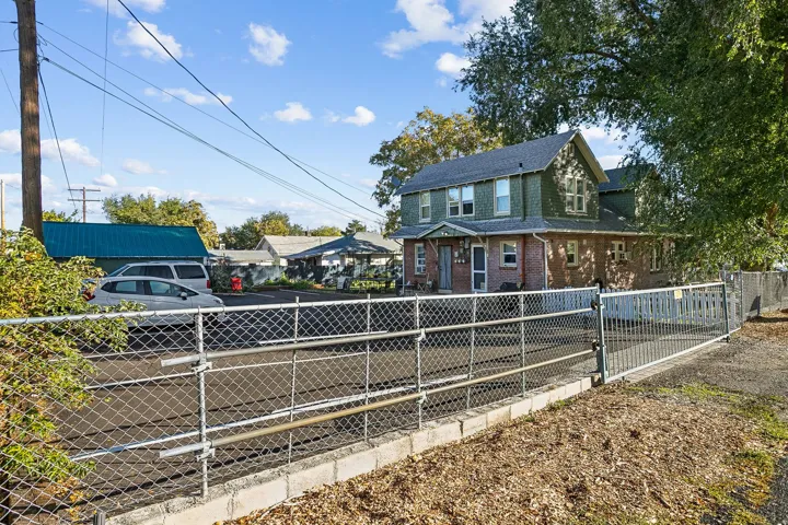 View of front of home featuring roof with shingles, a fenced front yard, and brick siding