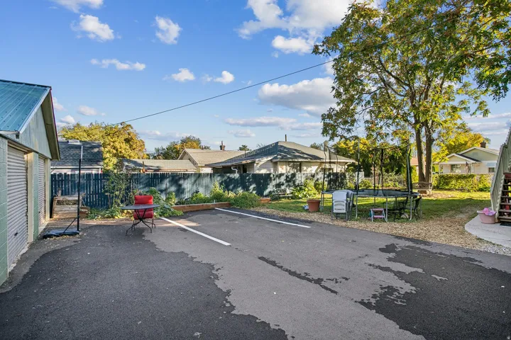 View of parking with a fenced backyard and a trampoline