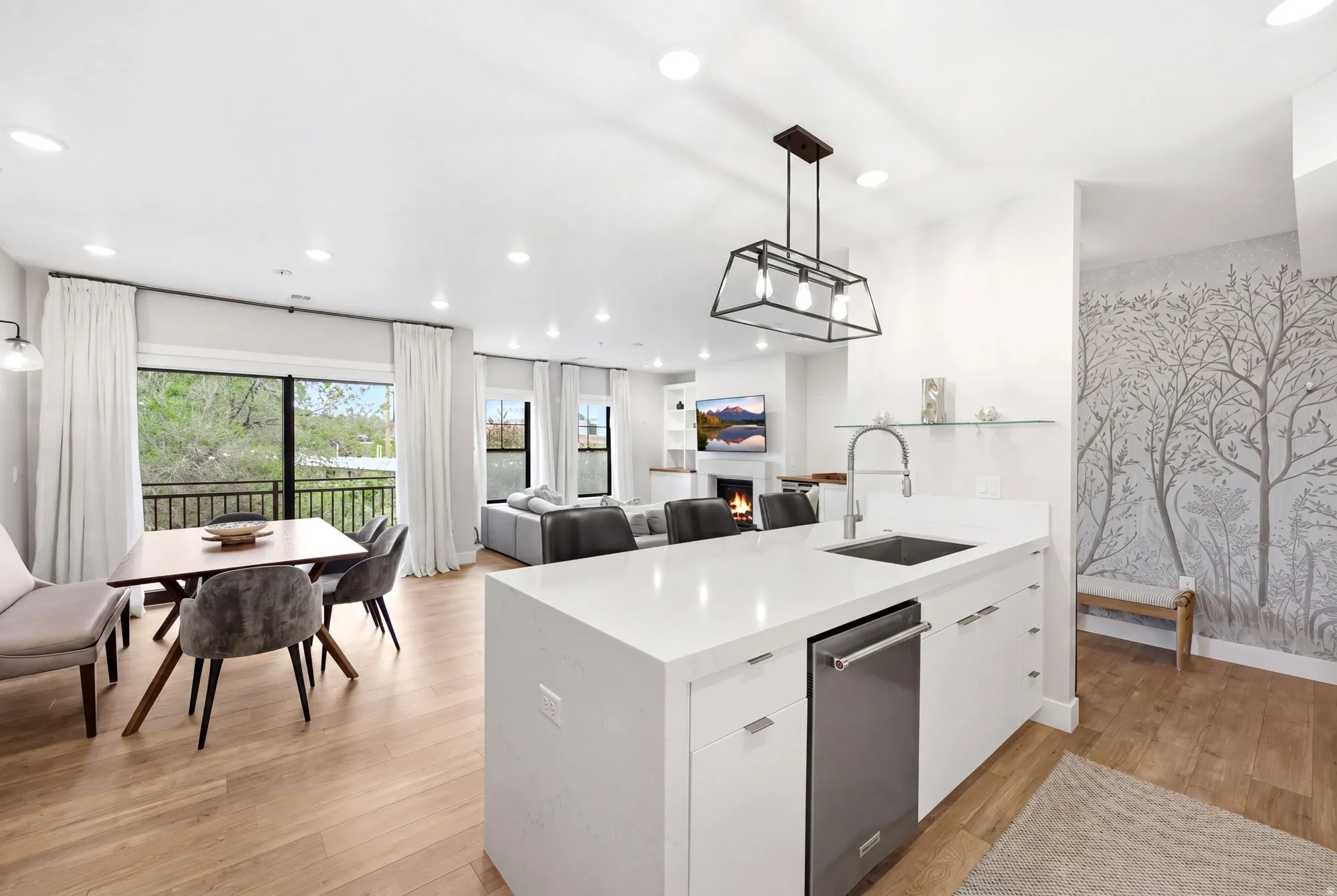 Kitchen with decorative light fixtures, white cabinets, a lit fireplace, open floor plan, and a peninsula