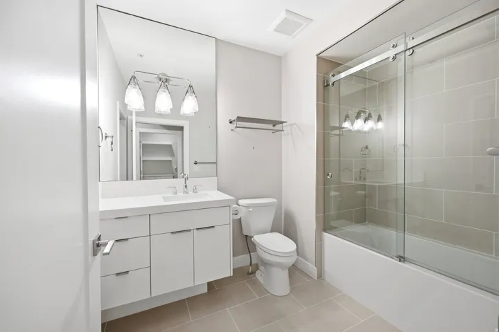 Bathroom featuring vanity, light tile patterned floors, and shower / bath combination with glass door