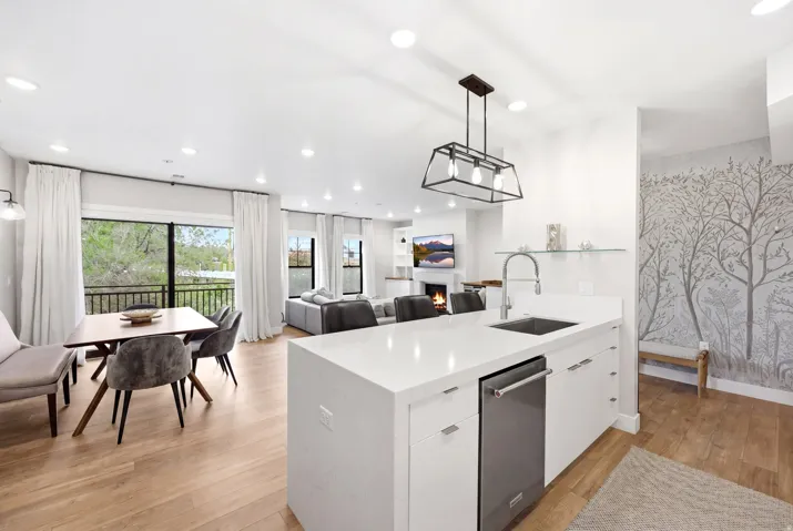 Kitchen with decorative light fixtures, white cabinets, a lit fireplace, open floor plan, and a peninsula