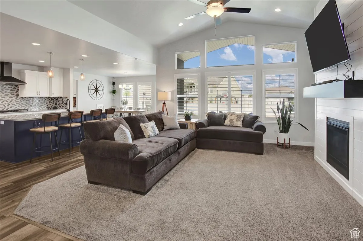 Living room featuring a glass covered fireplace, recessed lighting, high vaulted ceiling, and ceiling fan