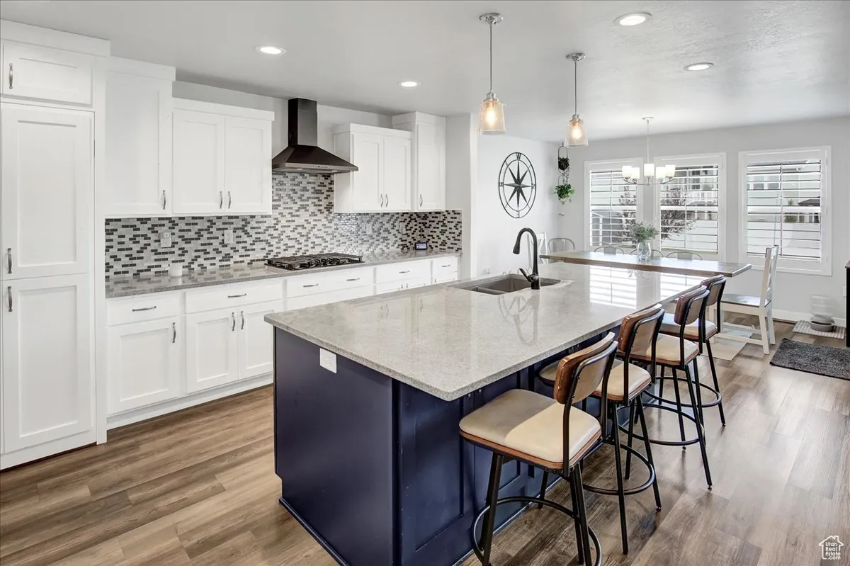 Kitchen with light stone counters, backsplash, white cabinetry, a breakfast bar area, and recessed lighting