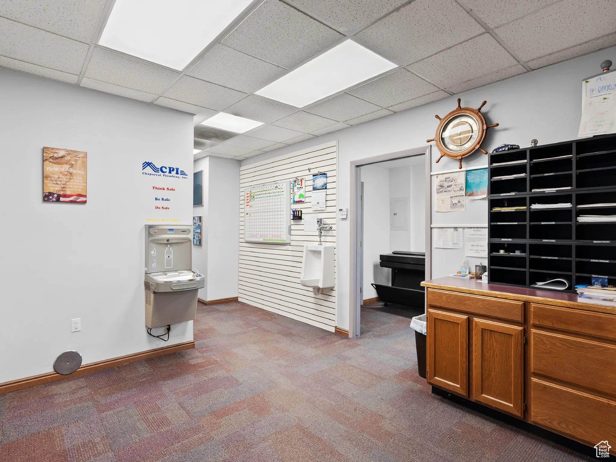 Office area with dark colored carpet and a drop ceiling