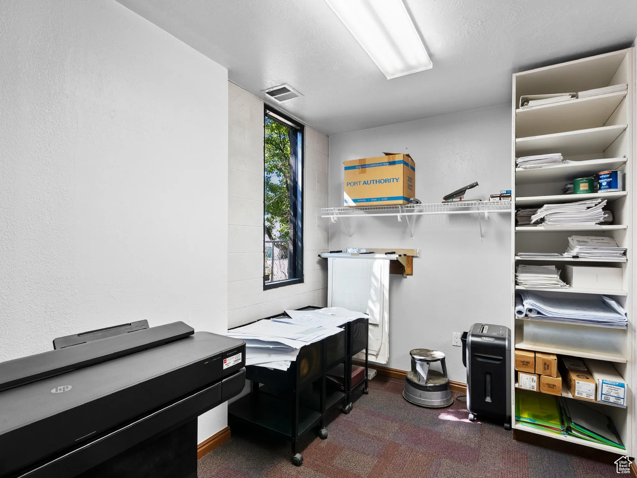 Home office featuring dark colored carpet and a textured wall