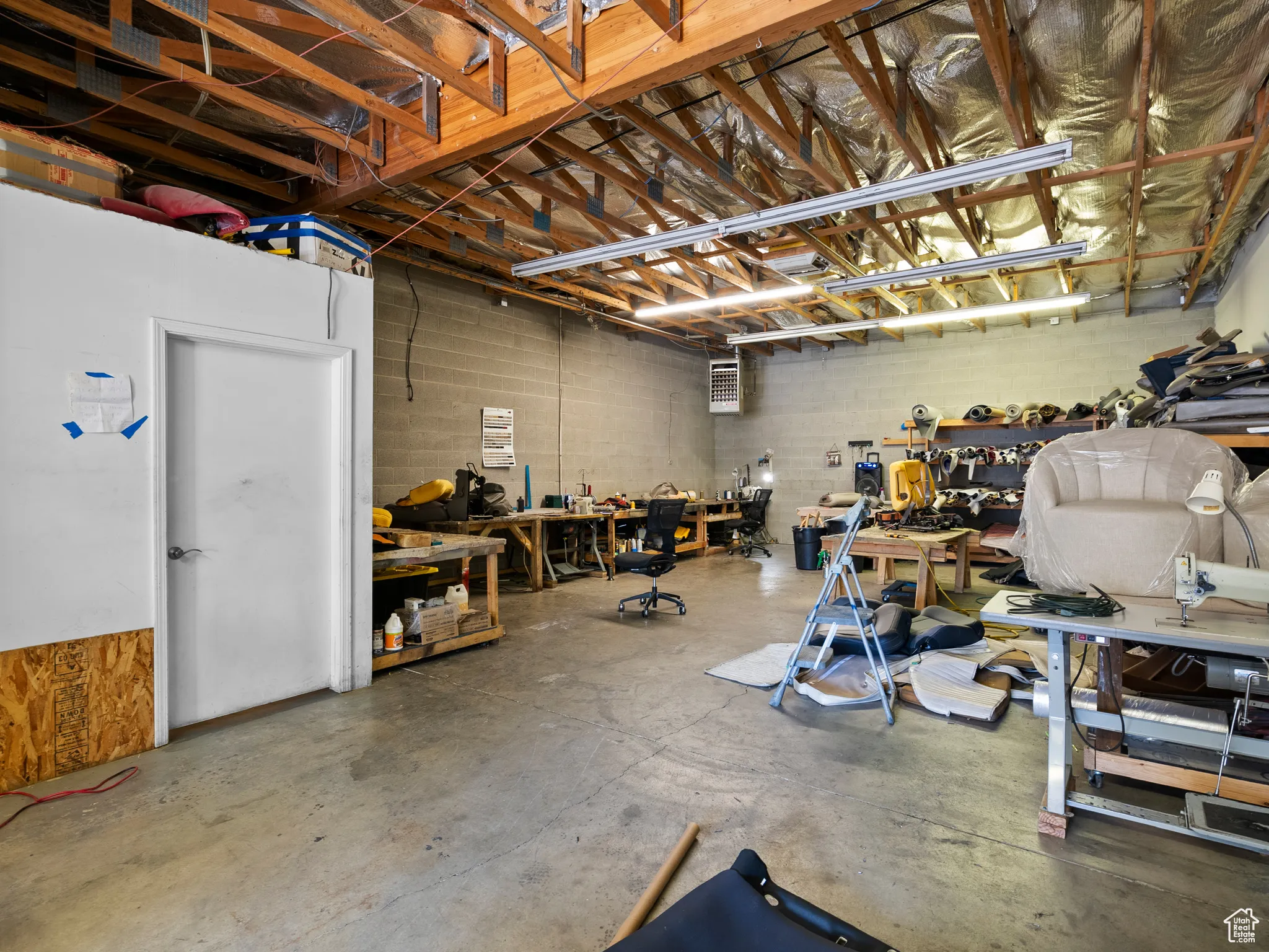 Garage featuring concrete block wall, a workshop area, and a heating unit
