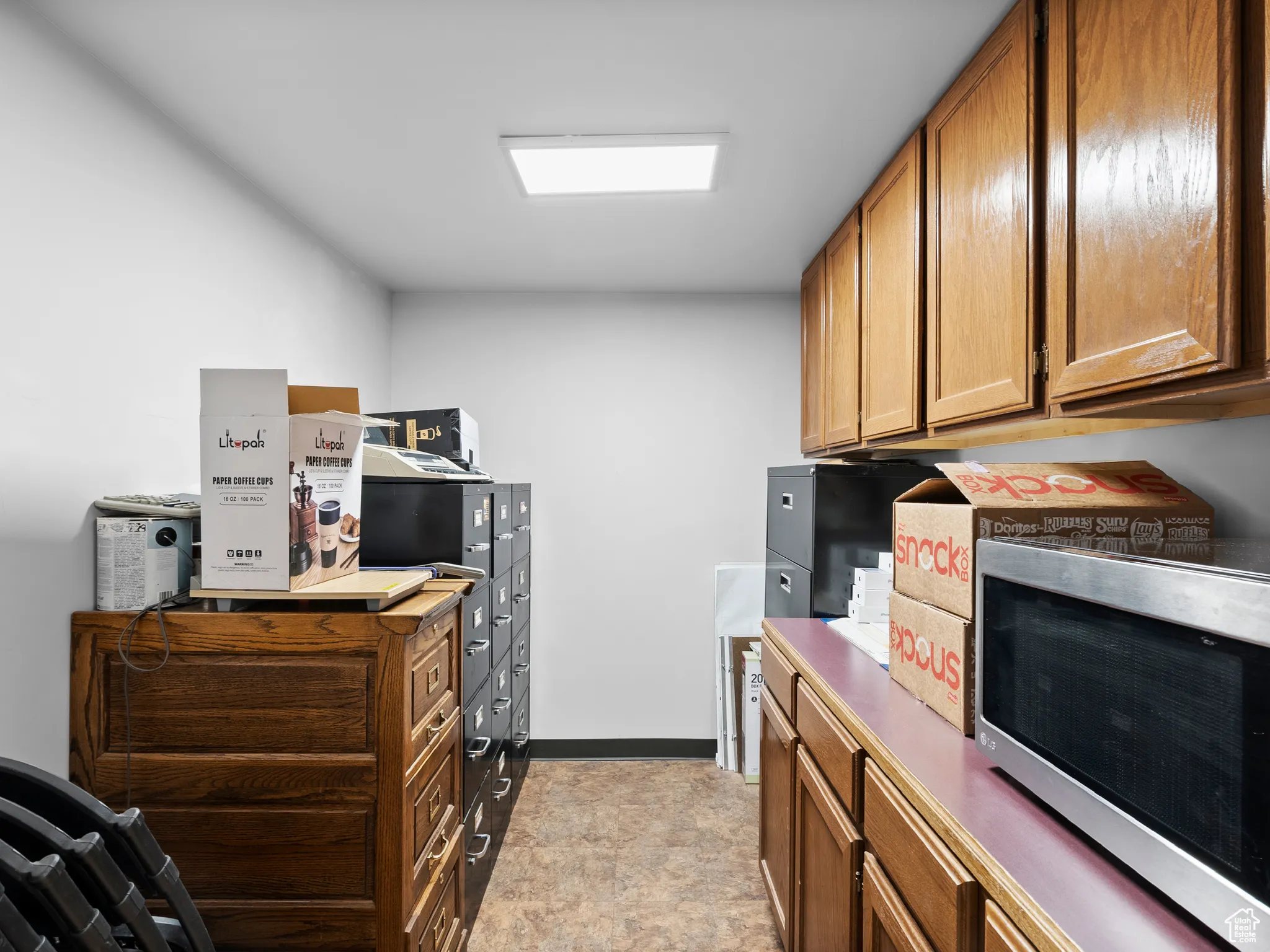 Kitchen featuring stainless steel microwave, brown cabinets, and stone finish flooring