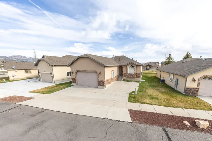 Ranch-style home with stucco siding, a residential view, a front yard, stone siding, and concrete driveway